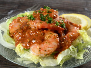 en un plato hay una base de ensalada y encima camarones con salsa