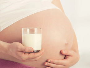 ¿Por qué es importante el calcio en el embarazo? Mujer embarazada, sosteniendo su vientre y un vaso de leche para consumir calcio en el embarazo.