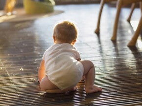 Bebé de ocho meses gateando en el piso de la sala.