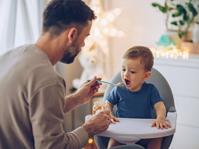 Padre alimentando a su hijo con papilla especial para niños. 
