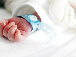 Mano de bebé recién nacido con pulsera de hospital