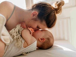 Mamá jugando en la cama con un bebé con texturas de tela.