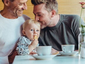 Niña comiendo galletas para bebés con su papá y abuelo