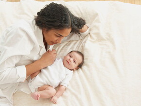 Conoce el desarrollo de un bebé de tres meses. Mamá acostada con su bebé de tres meses.