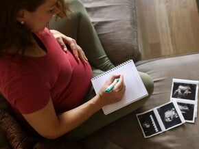 Tener un embarazo múltiple es muy común. Mamá con un cuaderno mirando la ecografía de su embarazo múltiple.