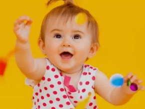 Bebé agarrando confeti delante de un fondo amarillo