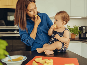 Mamá y niño pequeño en la cocina comiendo trozos de manzana.