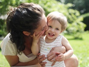 Mamá y niño pequeño sonriendo al aire libre en primavera.