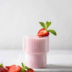 Un vaso contiene batido de fresa y la fruta de decoración