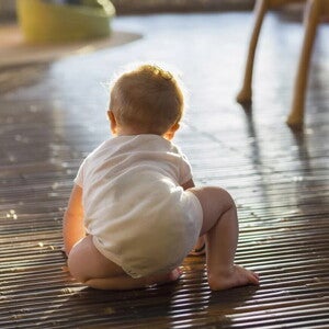 Bebé de ocho meses gateando en el piso de la sala.
