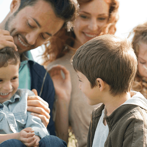 Una familia ensamblada con tres niños disfrutando juntos en el césped.