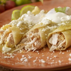 Tres burritos de pollo con salsa en un plato marrón