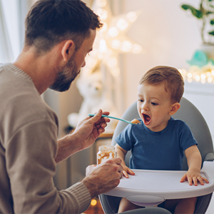 Padre alimentando a su hijo con papilla especial para niños. 