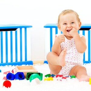 Es importante saber a los cuántos meses se sienta un bebé y acompañar este proceso Bebé sonriendo sentado al lado de sus juguetes