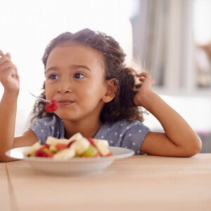 Niña vegetariana comiendo un plato de frutas