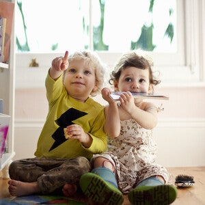 Niño y niña de dos años sentados en el piso, señalando. Concepto de comunicación y desarrollo de lenguaje.