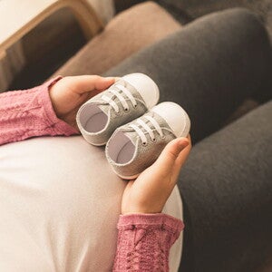 Conoce qué es el bebé arcoíris. Mamá embarazada de un bebé arcoíris cogiendo unos zapatitos.