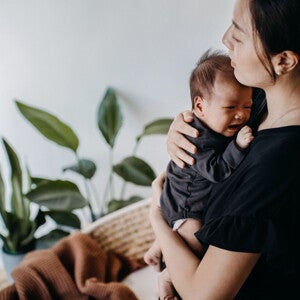Mamá alzando y consolando a su bebé que llora sin razón aparente.