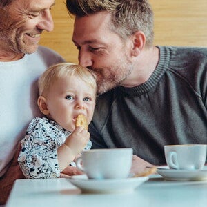Niña comiendo galletas para bebés con su papá y abuelo
