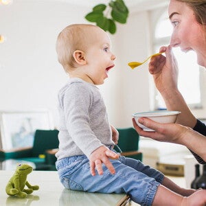 Bebé de 10 meses sentado comiendo con mamá