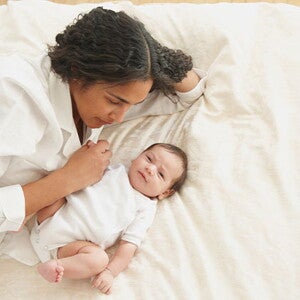 Conoce el desarrollo de un bebé de tres meses. Mamá acostada con su bebé de tres meses.