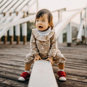 Conoce qué es el desarrollo psicomotor en los niños. Niña sorprendida sentada en un muro.