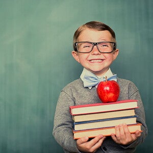 Niño sonriendo con libros en la mano.
