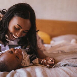 La mamá y el bebé haciendo ejercicios en la cama La mamá y el bebé haciendo ejercicios en la cama