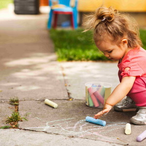 Niña pequeña dibujando en el piso.