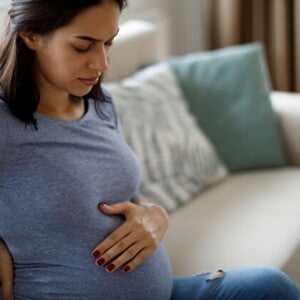 Conoce qué es la eclampsia y cuáles son sus causas. Mamá tocando el vientre y la espalda sintiendo molestia.