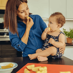 Mamá y niño pequeño en la cocina comiendo trozos de manzana.