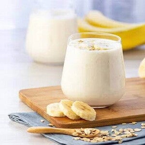 Un vaso con batido de plátano y plátanos alrededor