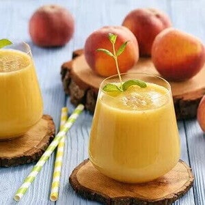 Dos licuados de naranja con durazno y frutas decorativas alrededor