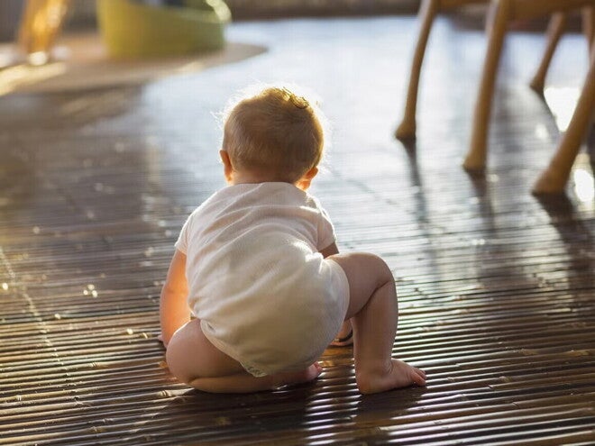 Bebé de ocho meses gateando en el piso de la sala.