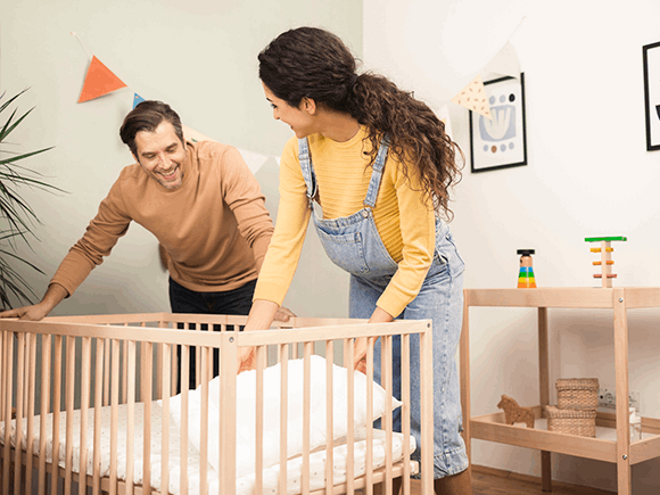Preparate para la llegada de tu bebé con nuestra guía completa Un hombre y una mujer preparan la cuna del bebe