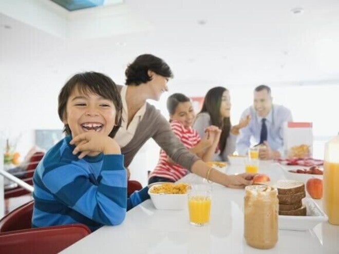 Familia el desayuno juntos en la cocina, sentados alrededor de la mesa.