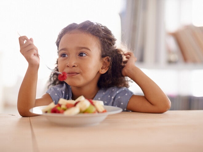 Niña vegetariana comiendo un plato de frutas