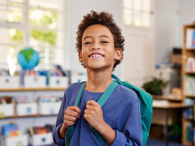 Niño con mochila sonriendo en su nuevo colegio