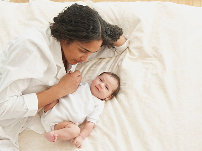 Conoce el desarrollo de un bebé de tres meses. Mamá acostada con su bebé de tres meses.