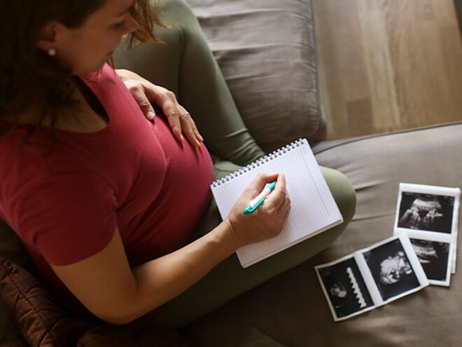 Tener un embarazo múltiple es muy común. Mamá con un cuaderno mirando la ecografía de su embarazo múltiple.