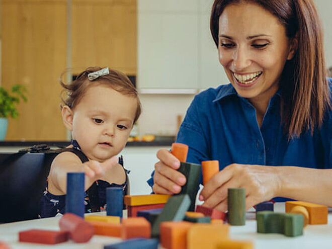 Bebé y mamá jugando con bloques La mamá y la bebé compartiendo con los bloques