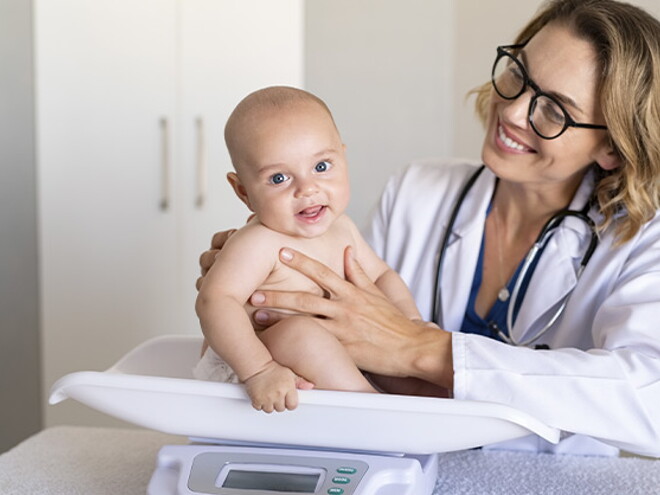 La tabla de peso en niños es un herramienta muy útil. Doctora pesando al bebé.