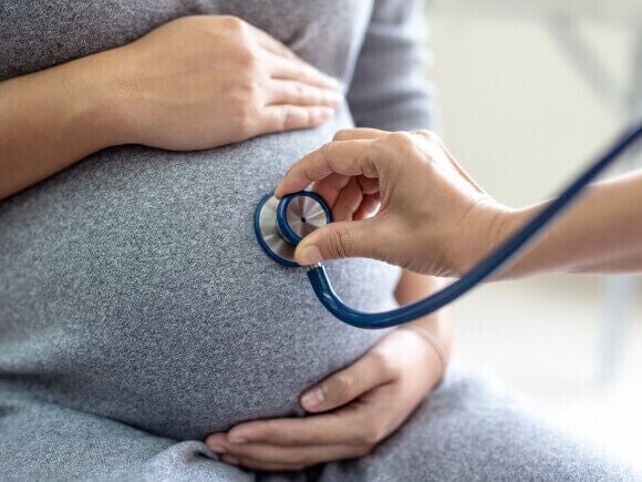 Médico revisando a una mujer embarazada durante una consulta prenatal