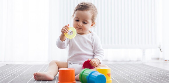 Las actividades fomentan el desarrollo de tu bebé de 8 meses Bebé de 8 meses sentado agarrando sus juguetes