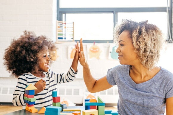 Niña pequeña y mamá jugando juntas, chocando los cinco.