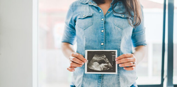 Conoce todos los cuidados en este nuevo embarazo. Mamá mostrando la ecografía de su bebé arcoíris en camino.