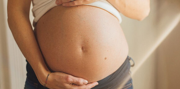 Conoce cuáles son las causas de la eclampsia. Mamá tocando el vientre.