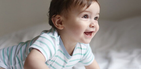 El gateo es fundamental en el desarrollo psicomotor. Niño sonriendo y gateando como parte del desarrollo psicomotor.