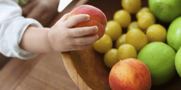 La mano de un niño en primer plano agarrando durazno La mano de un niño en primer plano agarrando durazno