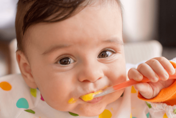 Niño sonriendo mientras come Niño sonriendo mientras come